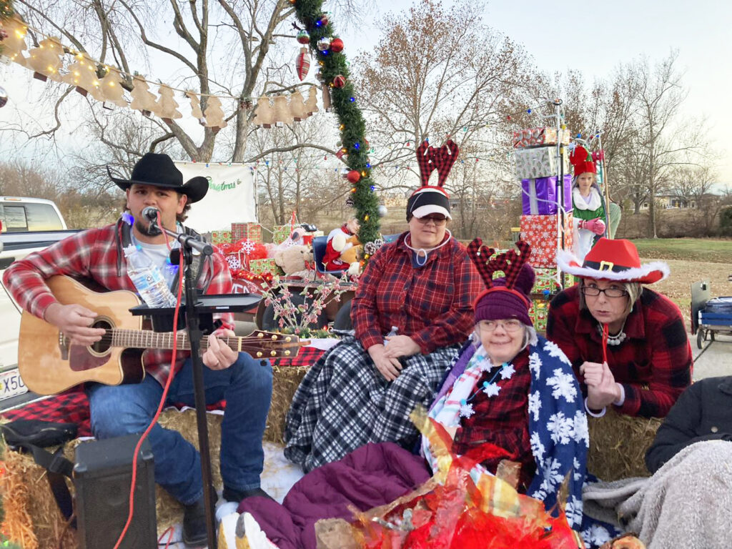 people on Christmas float with one playing guitar