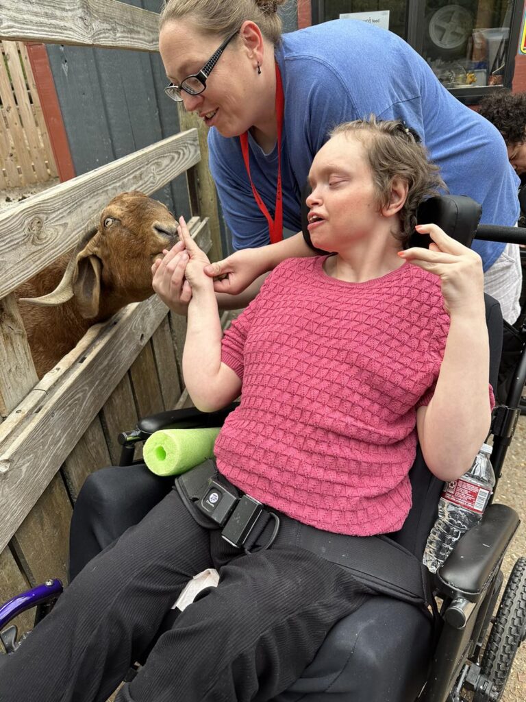 member petting a goat at the zoo