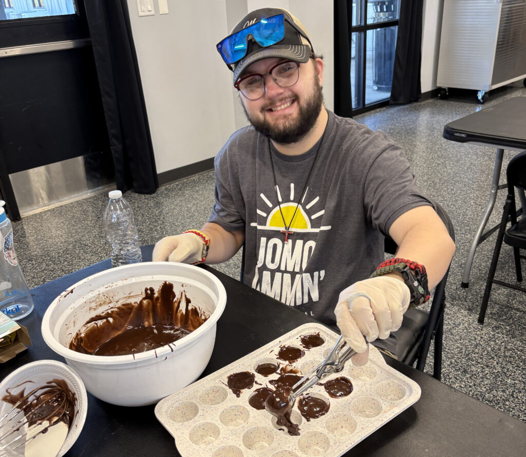 Member sitting at a table scooping batter into a mini muffin mold